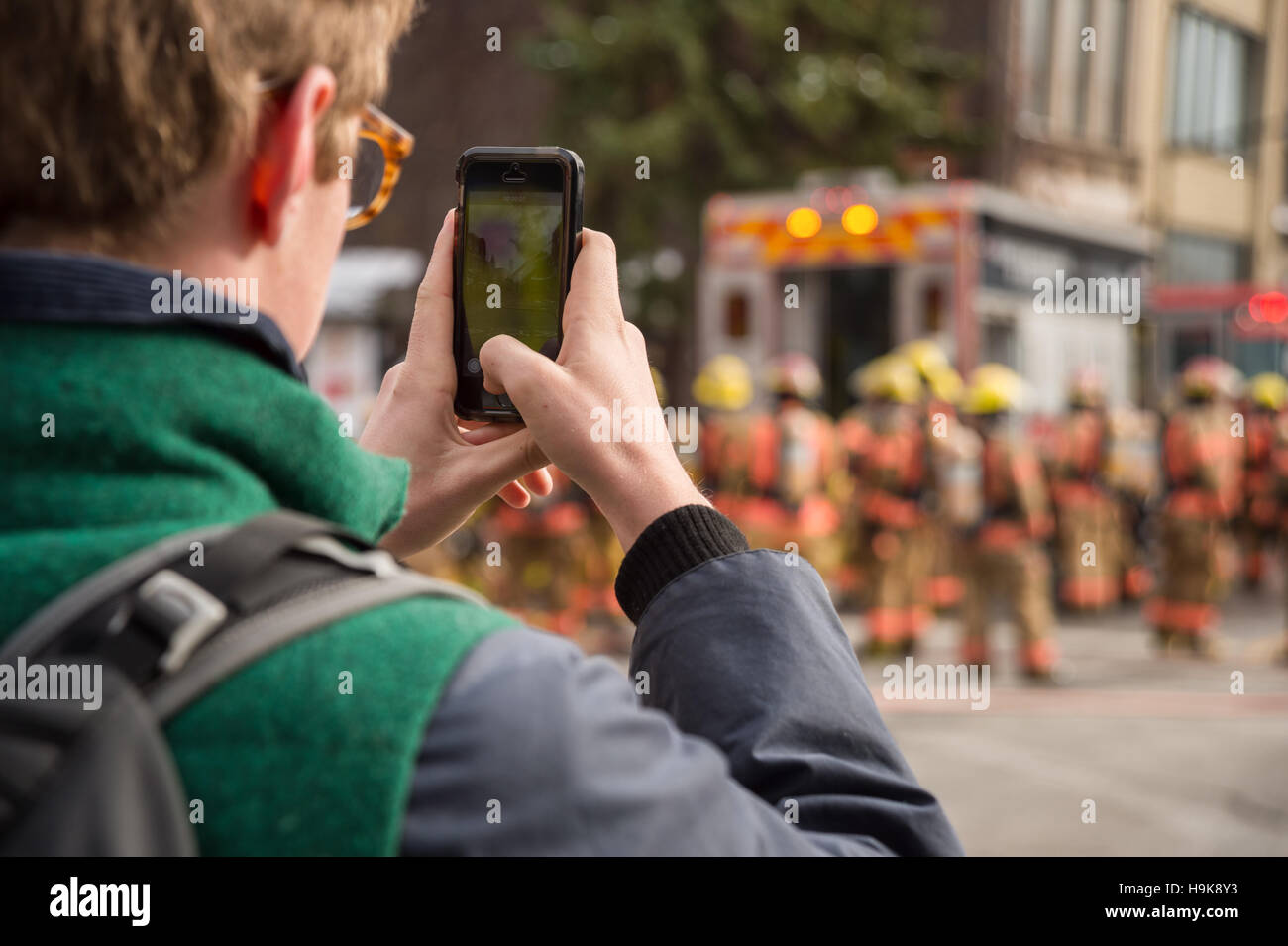 Montreal, Ca - 23. Nov. 2016: männlich Fußgängerzone Bilder nimmt mit Smartphone als Feuerwehrmänner auf 'Cafe Amusement 68' arbeiten Stockfoto
