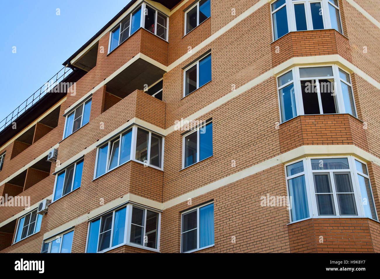 Balkone und Fenster ein mehrgeschossiges neues Haus. Neues Haus aus Ziegeln Stockfoto