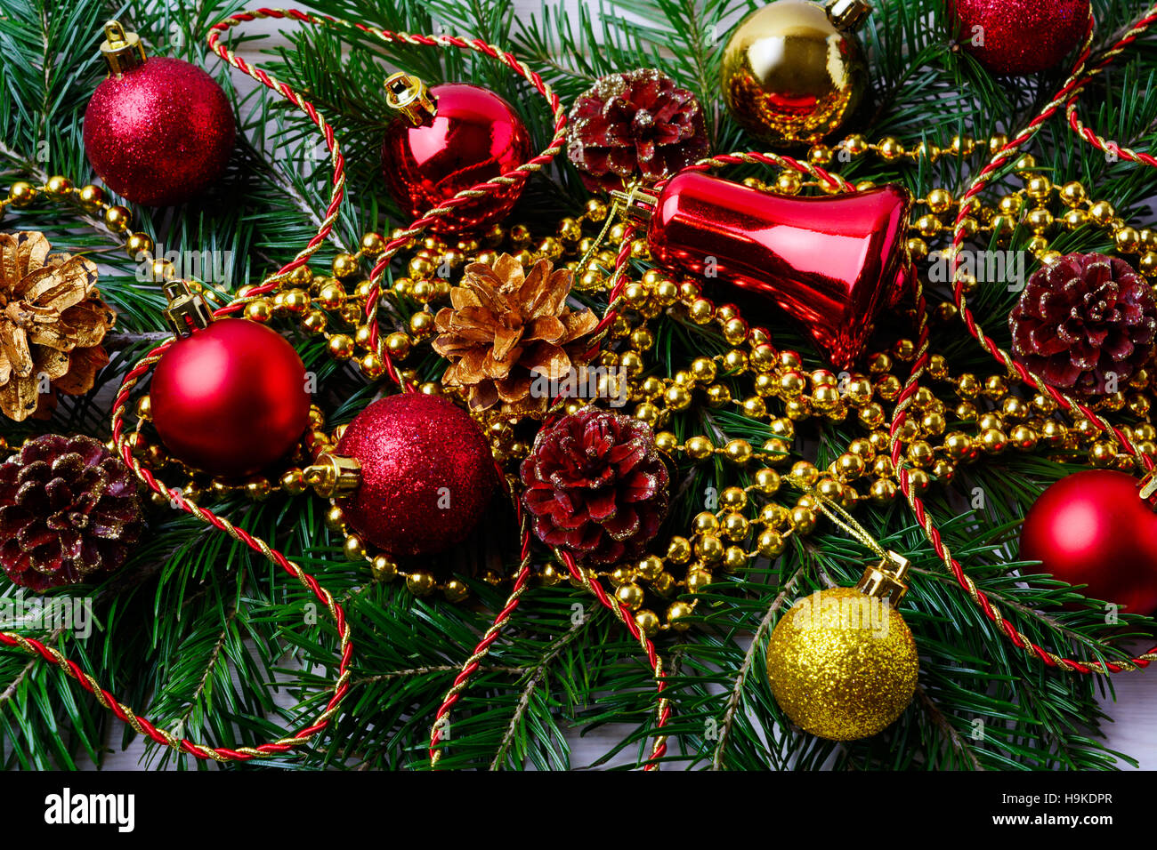 Roter Weihnachtsschmuck mit goldenen Perlen und Tanne Äste. Weihnachten Hintergrund mit roten Verzierungen. Stockfoto