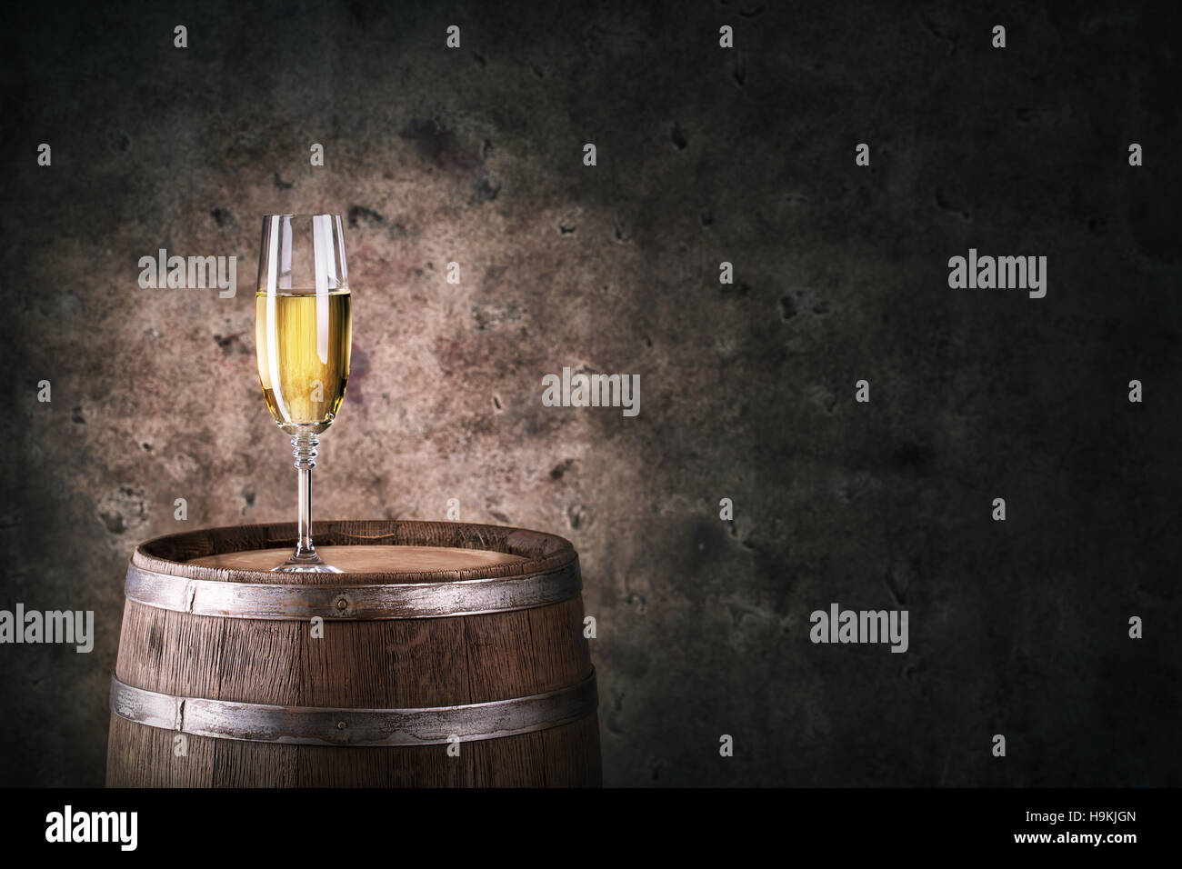 Glas Weißwein auf Holzfass auf dunklem Hintergrund Stockfoto