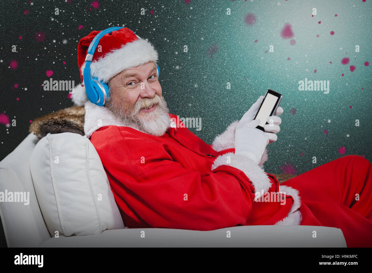 Zusammengesetztes Bild des Weihnachtsmannes mit Kopfhörer mit Handy Stockfoto