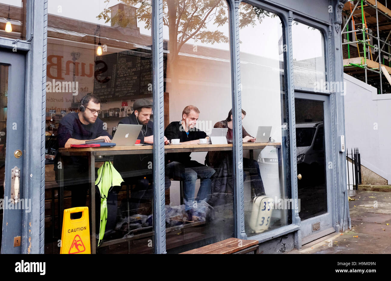 Islington London Großbritannien: Menschen, die ihren Computer im Fenster eines Cafés in der Islington High Street nutzen Stockfoto