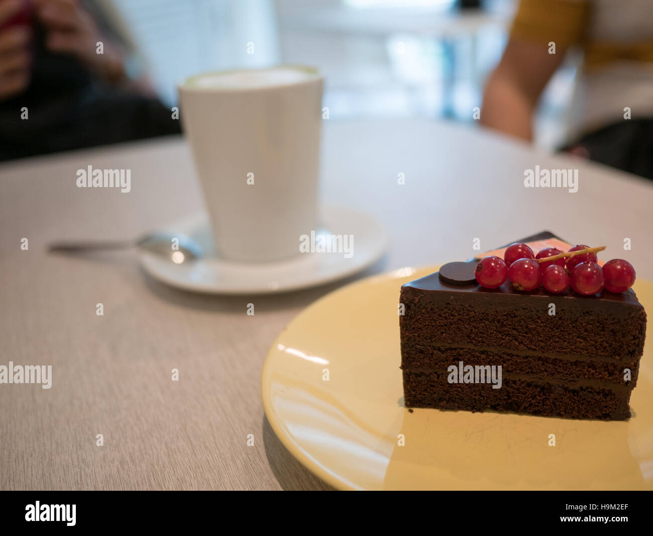 Stück Schokoladenkuchen auf eine gelbe Schale mit Café-Hintergrund Stockfoto