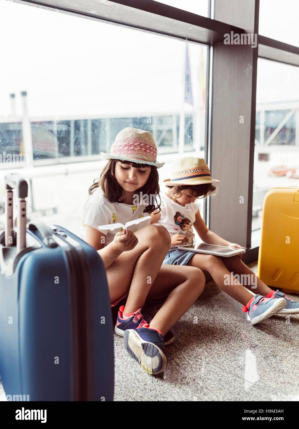 Zwei kleine Mädchen warten am Flughafen, mit digital-Tablette zu spielen Stockfoto