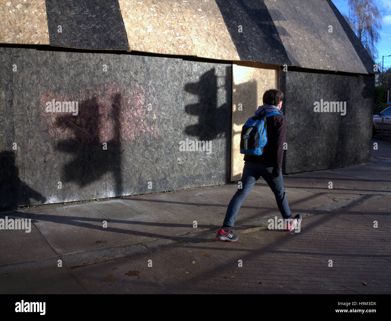 tief stehender Sonne auf städtischen einzelne Person zu Fuß alleine Schatten Ampel Stockfoto