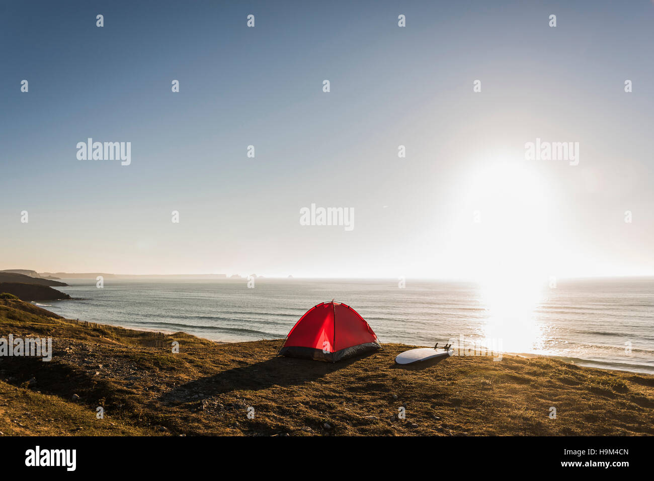 Rote Zelt und Surfbrett am Meer in der Abenddämmerung Stockfoto