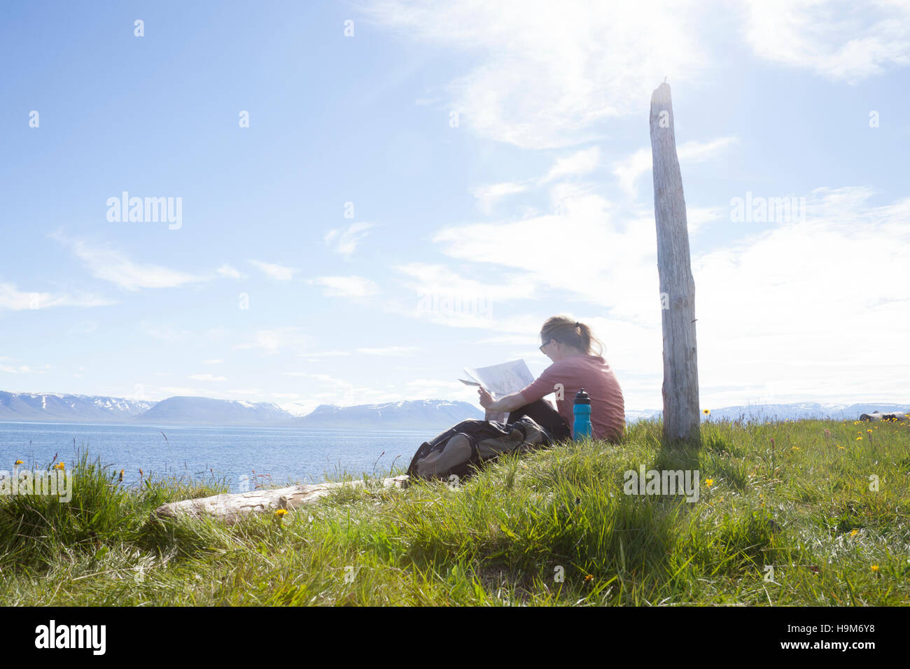 Island, Wanderer ruht auf einer Wiese Blick auf Karte Stockfoto