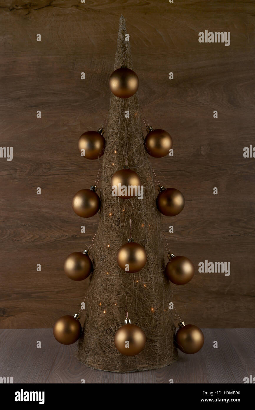 Dekorative Weihnachtsbaum gemacht aus Stroh mit goldenen Kugeln auf hölzernen Hintergrund isoliert Stockfoto