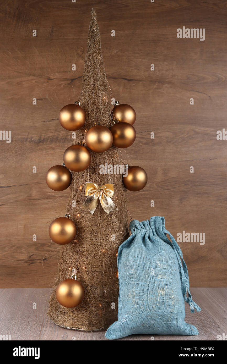 Dekorative Weihnachtsbaum aus Stroh mit goldenen Kugeln und blaue Geschenke Jutesack auf hölzernen Hintergrund gemacht Stockfoto