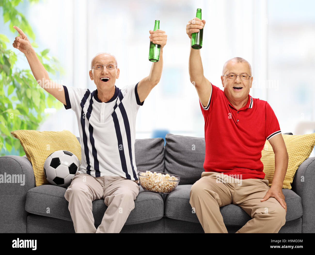 Überglücklich Senioren sitzen auf einem Sofa Fußball gucken und jubeln Stockfoto