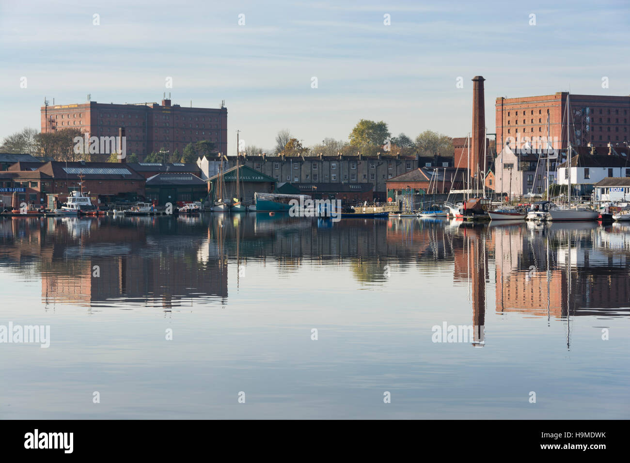 Die historischen Underfall Yard am Bristols Floating Harbour, mit einem Kamin aus rotem Backstein und Lagerhallen hinter. Stockfoto