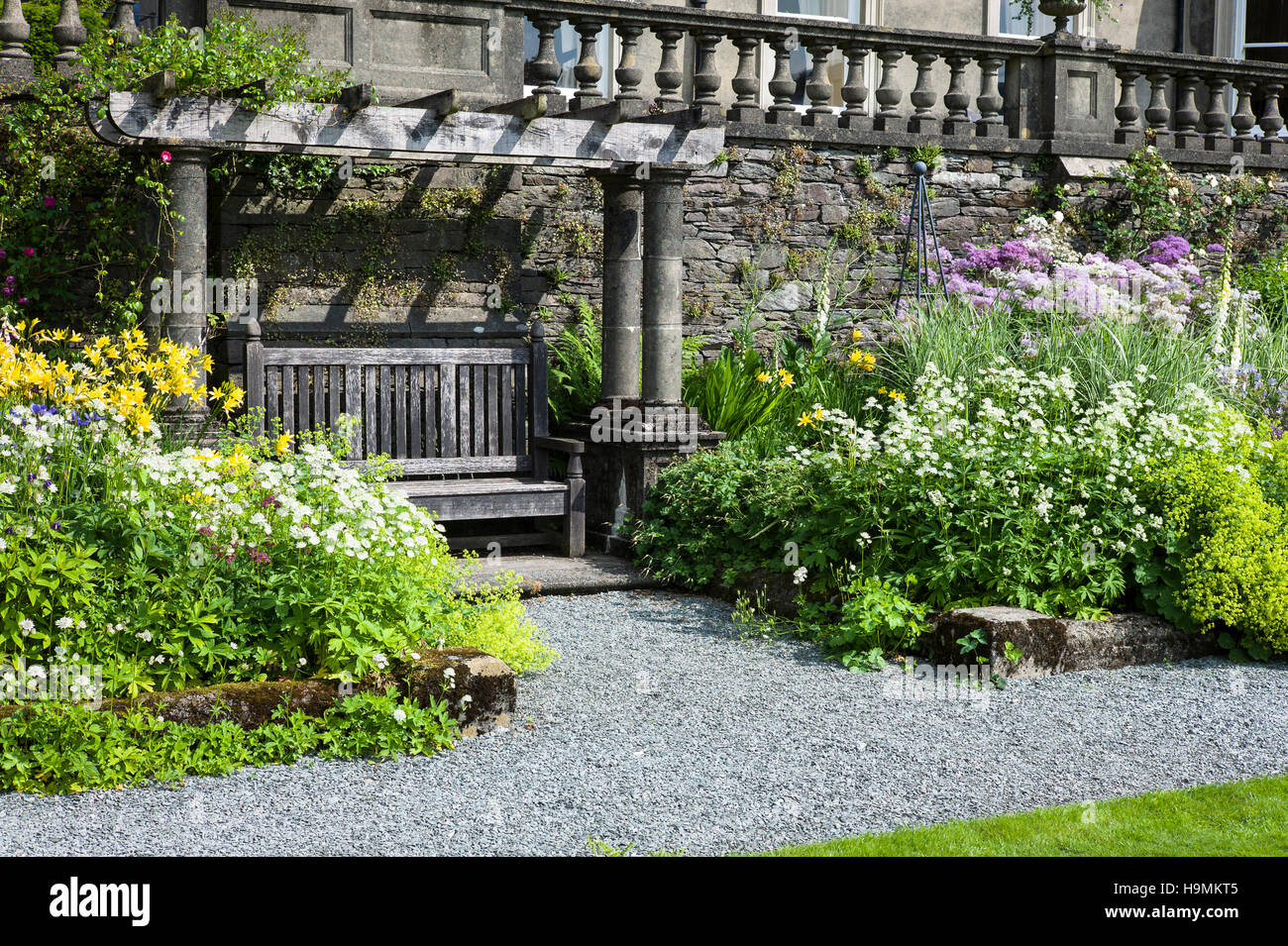 Ein Sitzmöbel Arbor flankiert von krautigen Blumenrabatten in Rydal Hall Cumbria UK Stockfoto