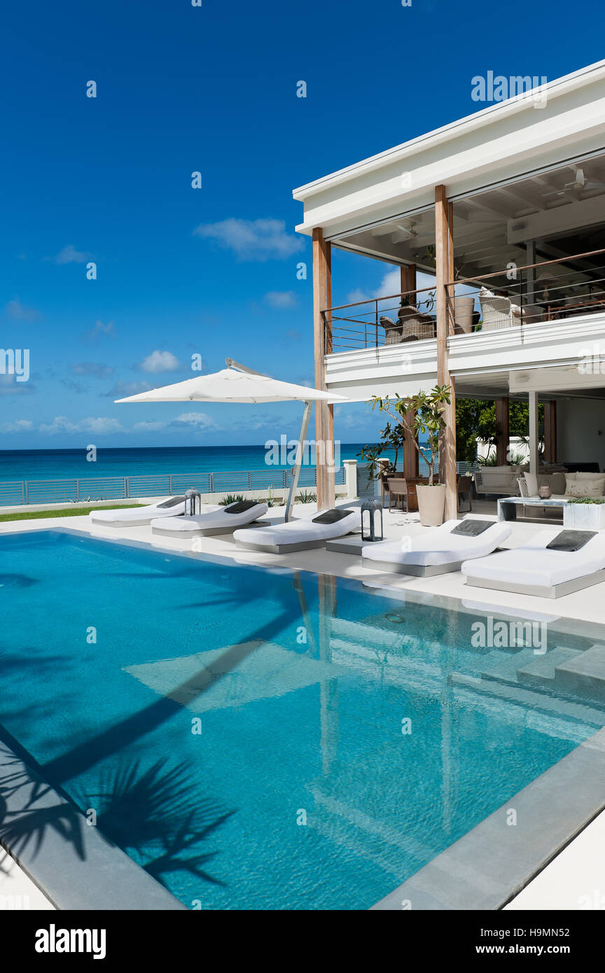 Sonnenliegen am Pool in Luxus-Unterkunft mit Blick auf Meer, Barbados, Karibik, West Indies Stockfoto