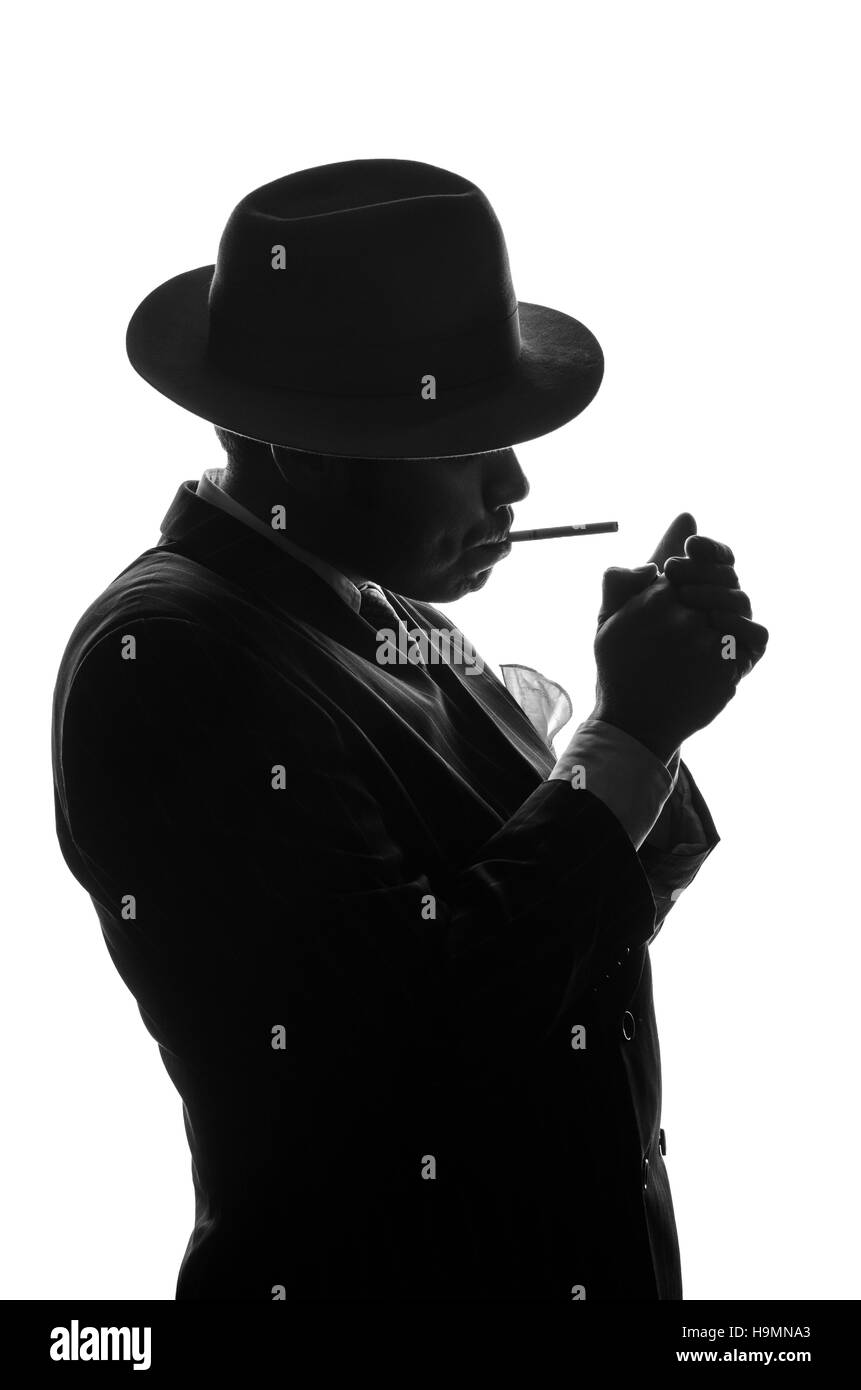 Silhouette der Privatdetektiv zündet die Zigarette. Agent sieht aus wie Al Capone bleiben Seite zur Kamera. Polizei kriminelle Szene in schwarz und weiß. Gangster-Studio gedreht Stockfoto