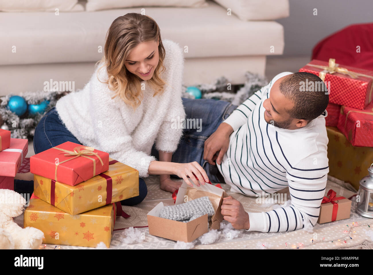 Ziemlich neugierig Frau ihr Geschenke auspacken Stockfoto