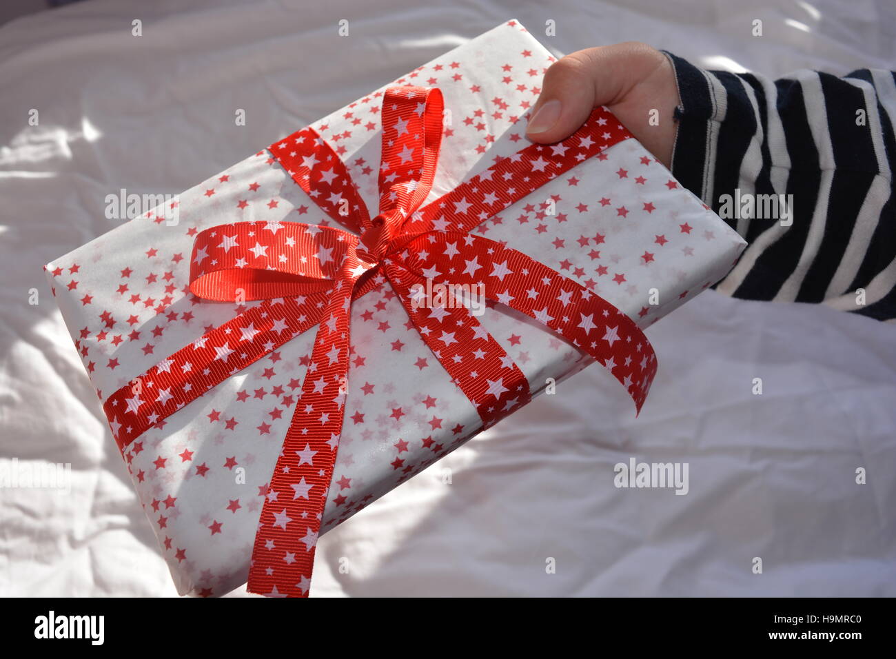 Frau hält eine schön verpackte Weihnachtsgeschenk verziert mit einem roten Band Stockfoto