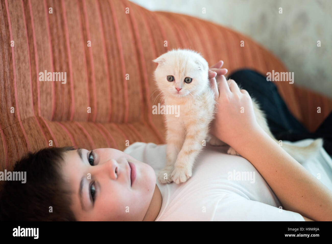 Teenboy mit einem Kätzchen auf Couch liegen Stockfoto