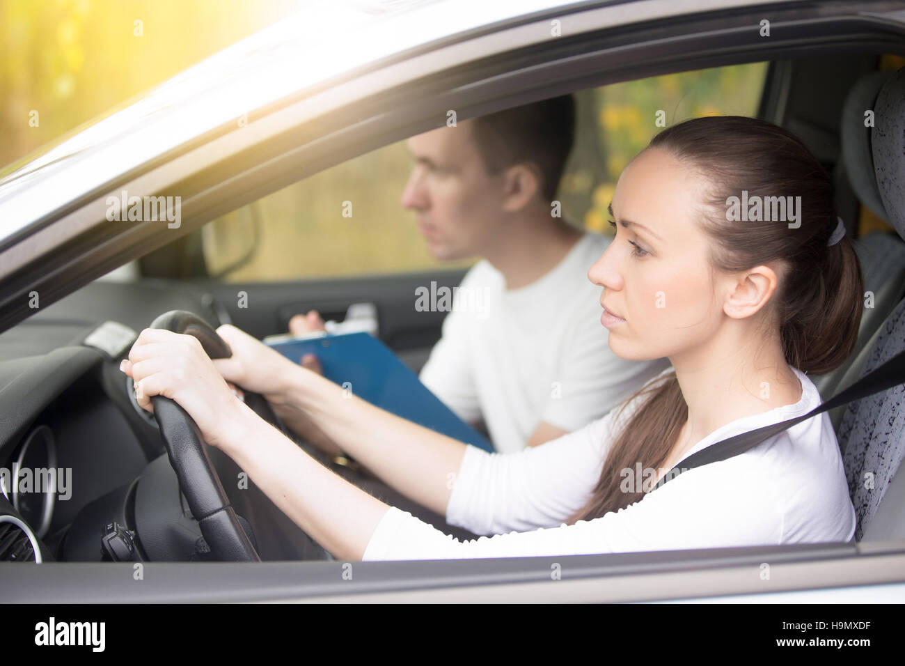 Fahrprüfung. Junge Frau, die Auto fahren, Mann sitzt beiseite Stockfoto