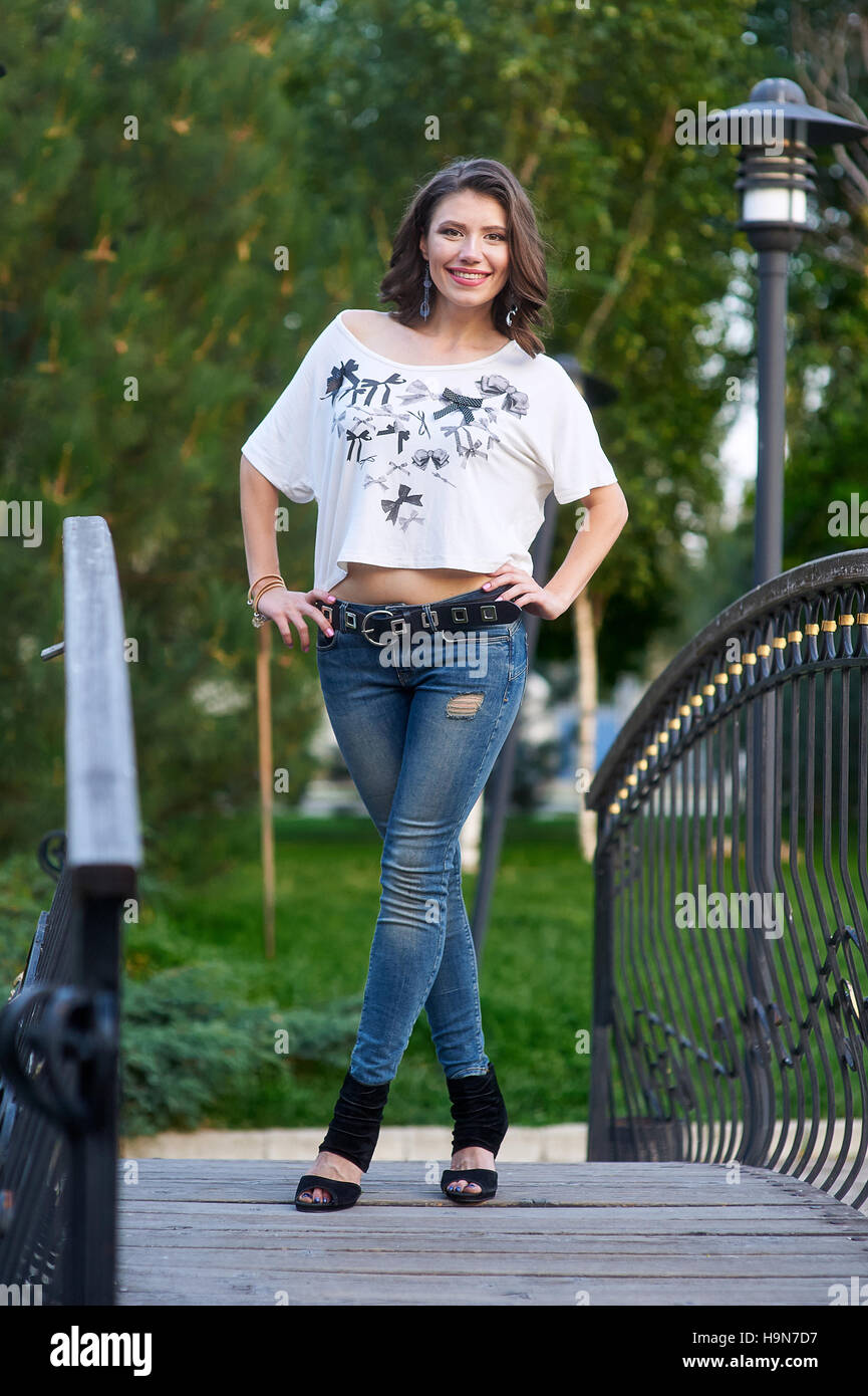 junge Frau in Jeans und T-shirt auf einer Brücke Stockfoto