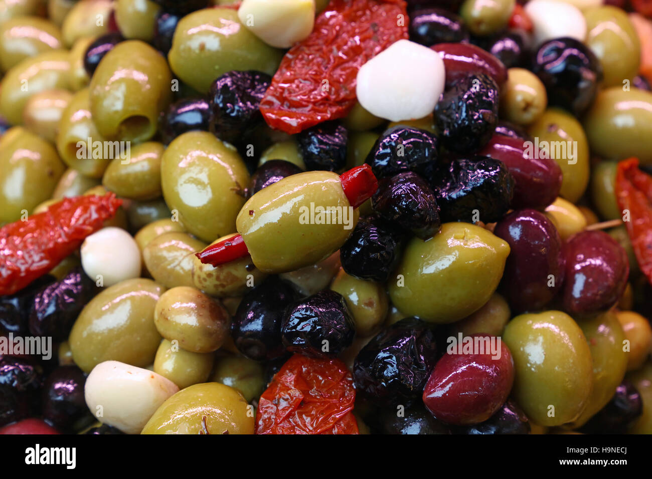 Mediterraner Salat-Mix von sortierten ganzen italienischen Oliven (schwarz, grün, rot) mit Knoblauch, Paprika und getrocknete Tomaten in Öl zu schließen, bis, low angle vi Stockfoto
