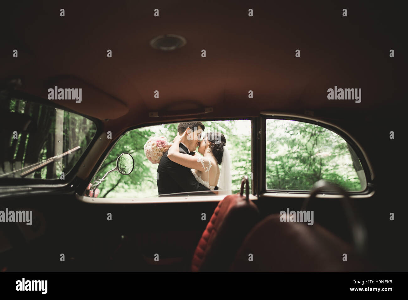 Glückliche Brautpaar, Mann und Frau in der Nähe von stilvollen Retro-Auto küssen Stockfoto