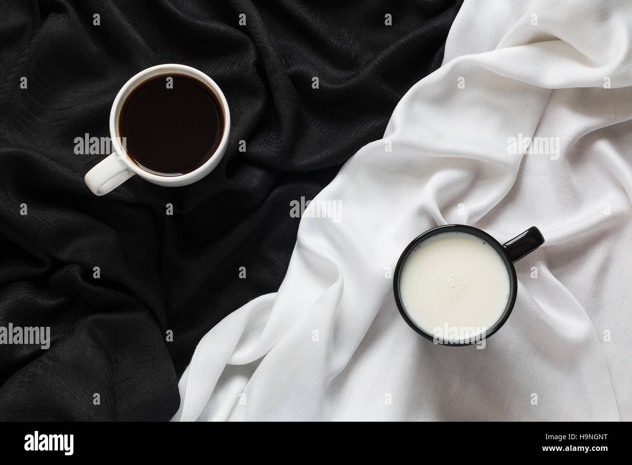 Zwei Tassen Kaffee und Milch auf dem schwarzen oder weißen Stoff. Ansicht von oben. Stockfoto