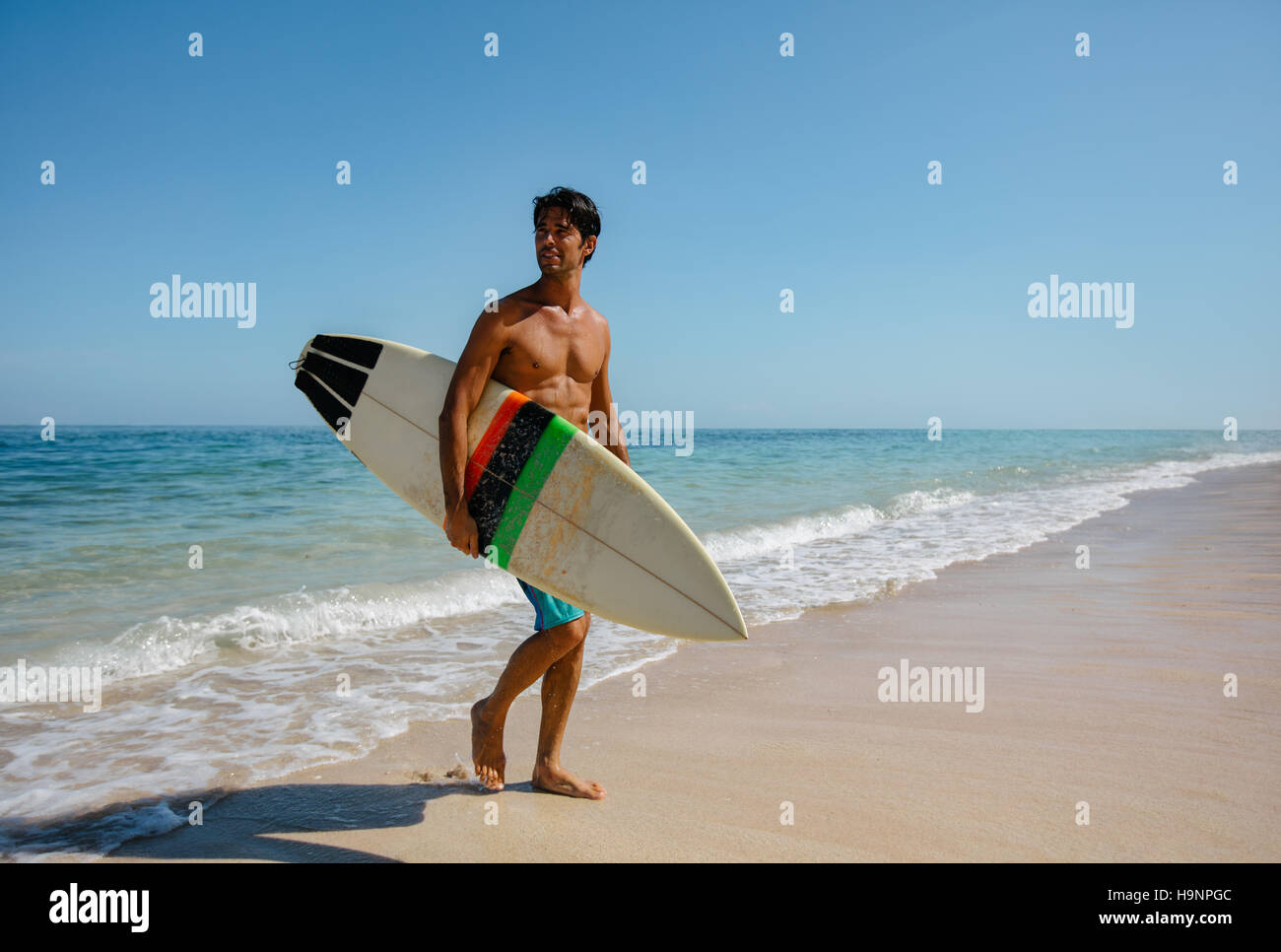 Voller Länge Schuss des jungen Mannes mit Surfbrett am Strand. Gut aussehend kaukasischen männlichen Holding Surfbrett zu Fuß am Ufer Meeres und wegsehen. Stockfoto