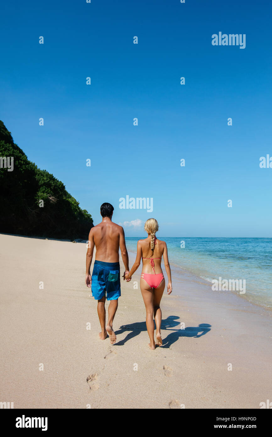 Rückansicht-Schuss von paar in den Flitterwochen Hand in Hand zu Fuß entlang der Küste. Paar in Liebe erholsamen Sommer-Urlaub am Strand. Stockfoto