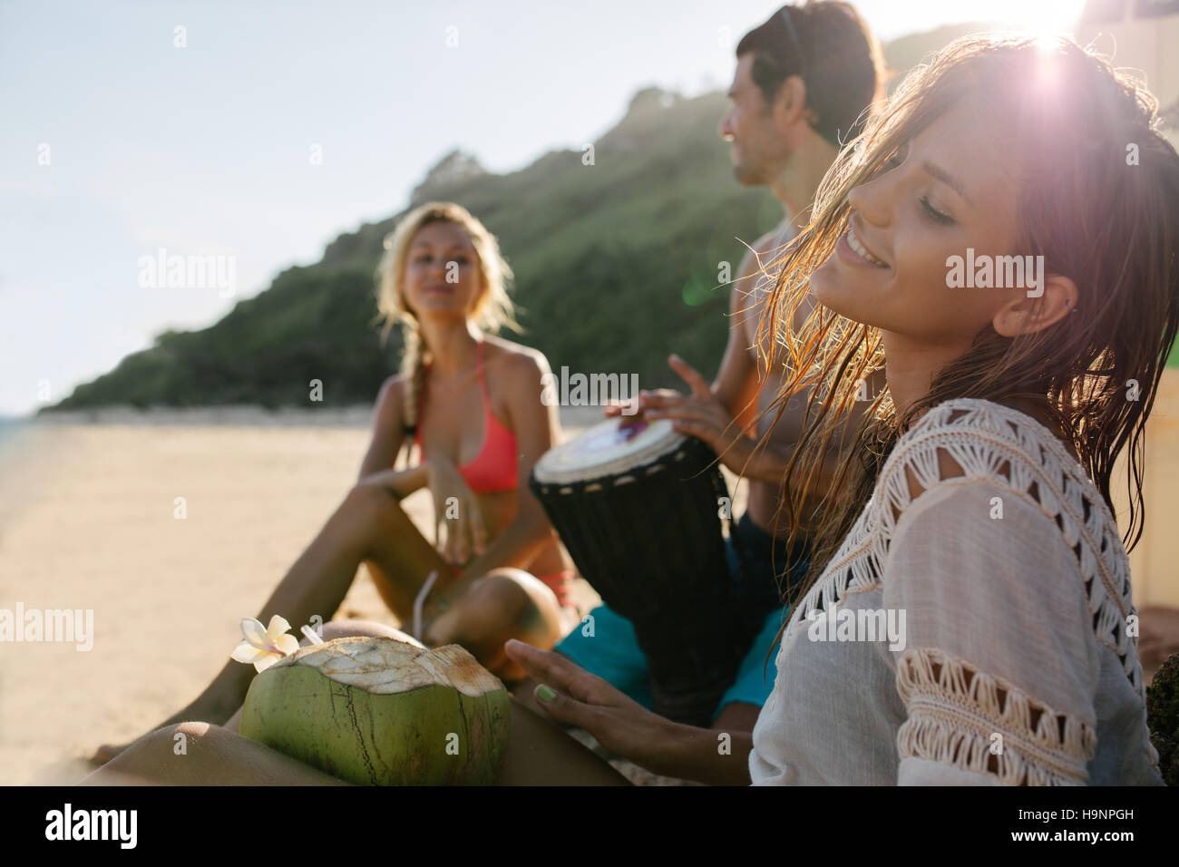 Junge Frau Entspannung am Meer mit ihren Freunden im Hintergrund. Freunde, Party und Spaß am Strand. Stockfoto