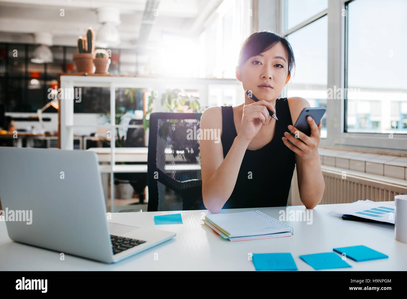 Porträt von zuversichtlich asiatische Frau sitzt an ihrem Schreibtisch mit Handy. Asiatische Geschäftsfrau im Büro arbeiten. Stockfoto