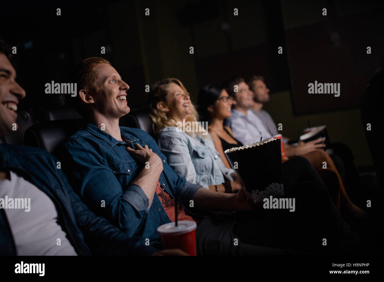 Gruppe von Freunden sitzen im multiplex-Kino mit Popcorn und Getränken. Junge Menschen Film im Kinosaal. Stockfoto