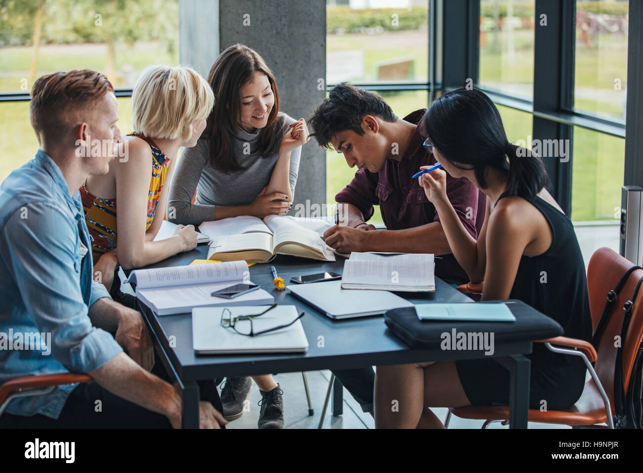 Junge Leute sitzen am Tisch arbeiten im Auftrag der Schule. Gemischtrassigen Gruppe von Studenten zusammen in einer Bibliothek. Stockfoto