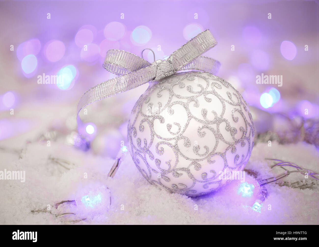 Silberne Weihnachtskugel und Schnee auf Defocused Xmas lila Bokeh Stockfoto