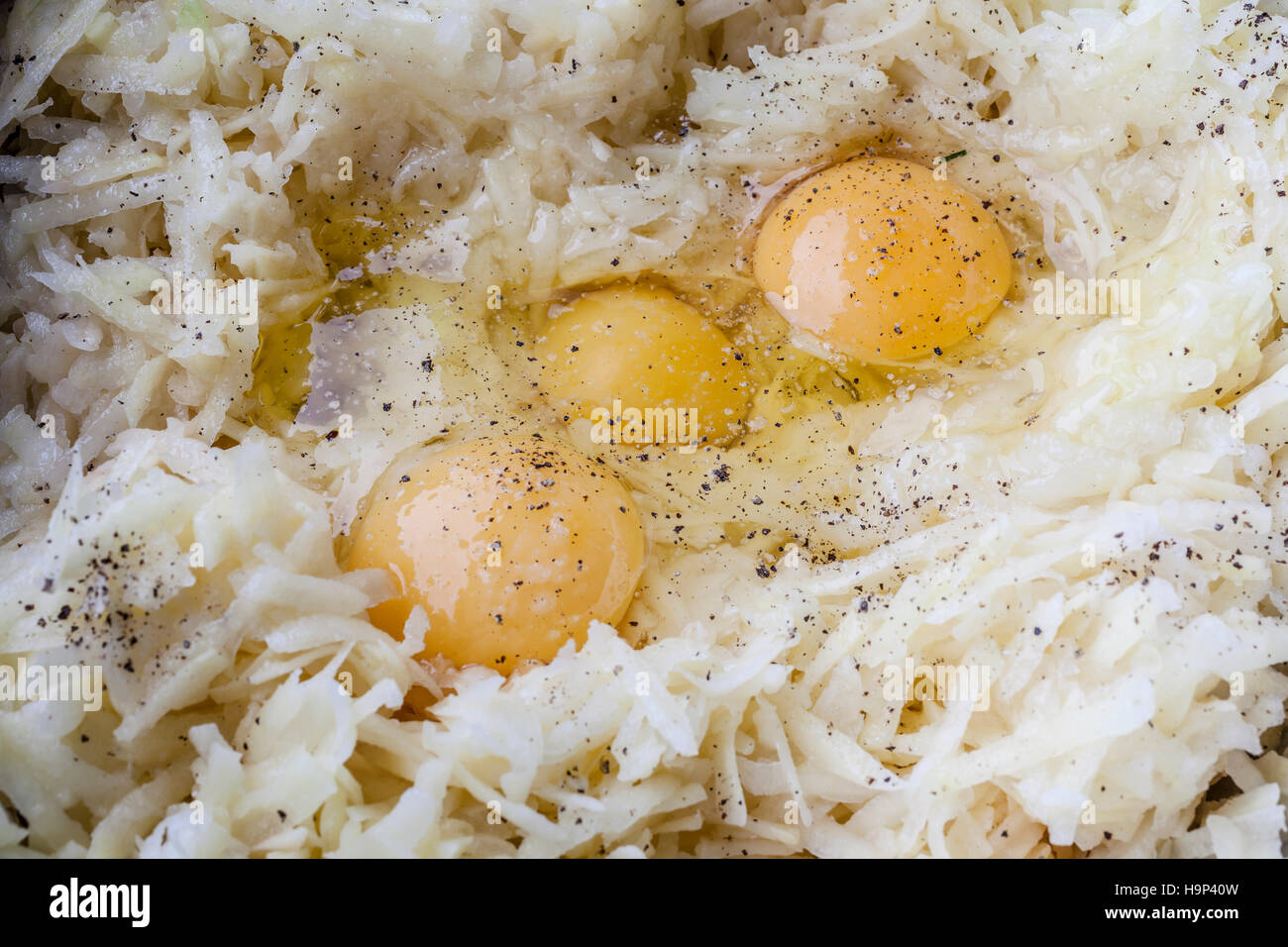Geriebene Kartoffel und drei Eiern mit Würze für Latkes in Metall-Behälter von oben closeup Stockfoto