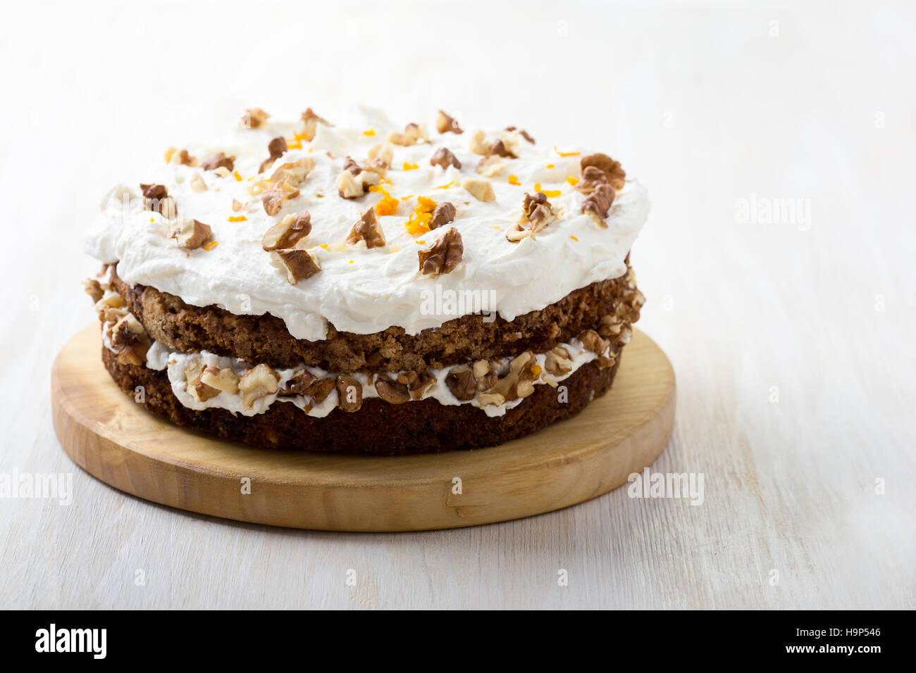 Hausgemachte Karotte und Walnuss-Kuchen mit pikanter orange Sahnehäubchen auf weißer Holztisch Stockfoto