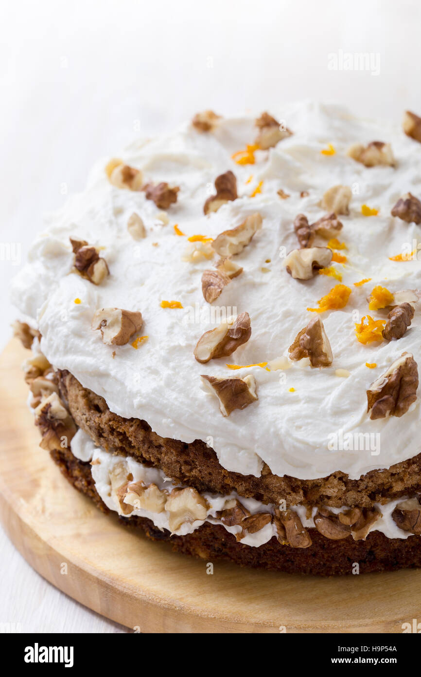 Hausgemachte Karotte und Walnuss-Kuchen mit pikanter orange Sahnehäubchen auf weißer Holztisch Stockfoto