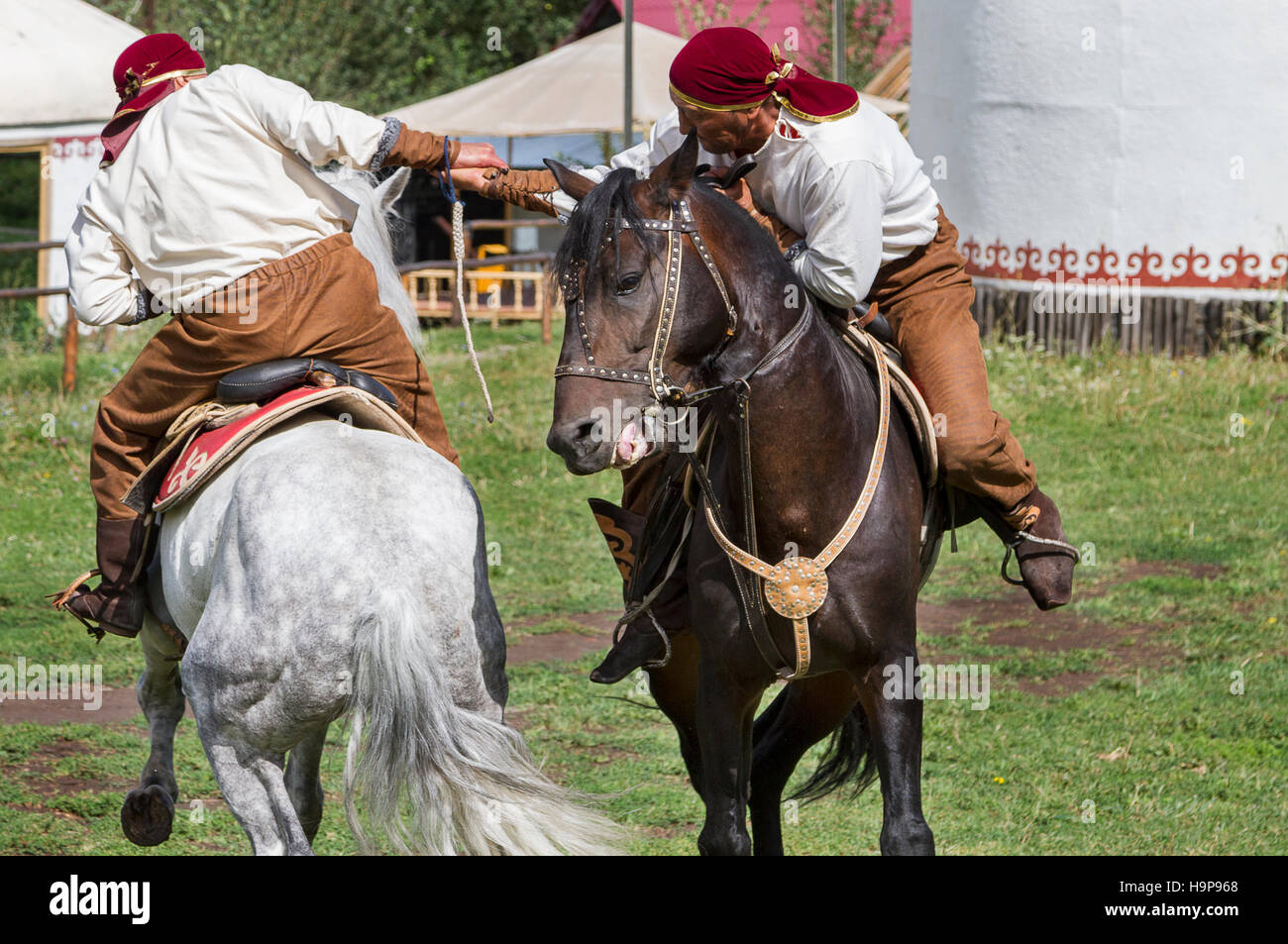 Kasachische Männer machen traditionelles nomadisches Armringen auf ihrem Pferd, in Kasachstan. Stockfoto