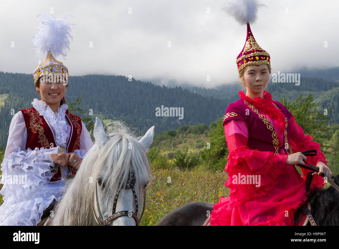 Kasachische Mädchen in Volkstrachten reiten auf ihrem Pferd in Almaty, Kasachstan Stockfoto