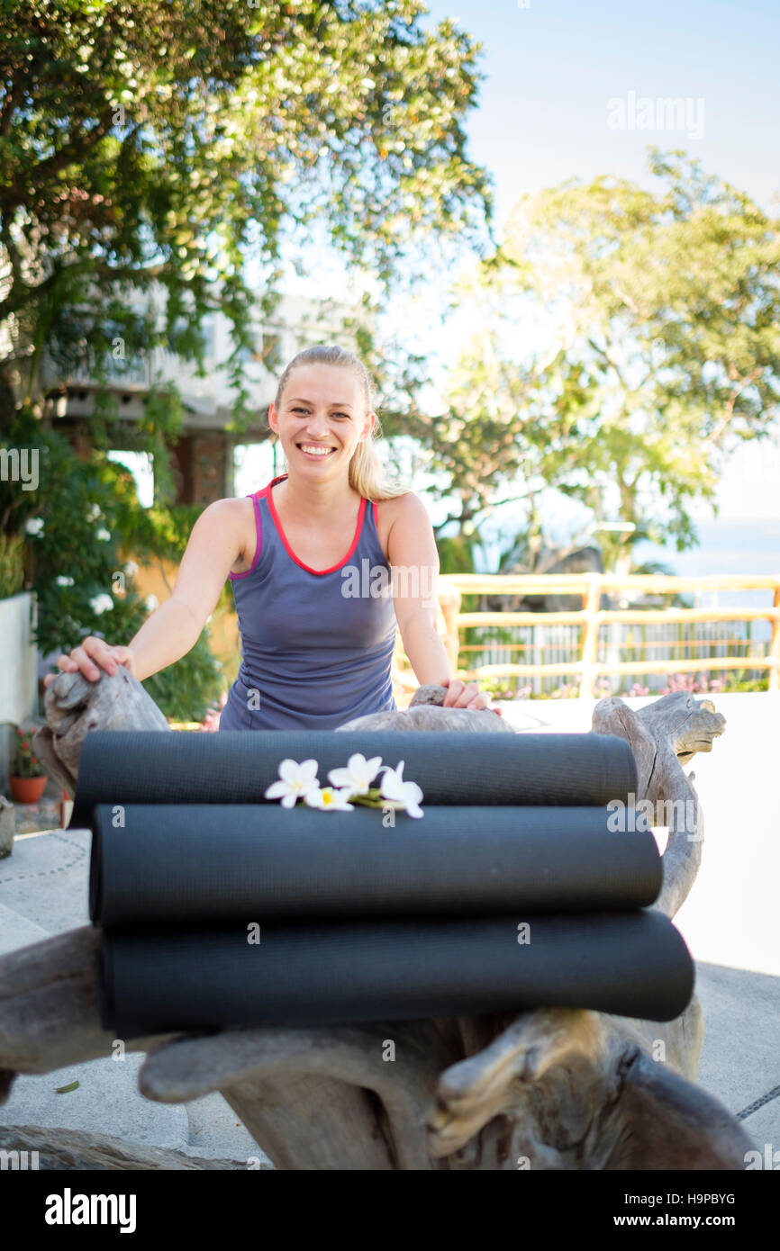Junge Frau lächelnd über aufgerollt, Yoga-Matten Stockfoto
