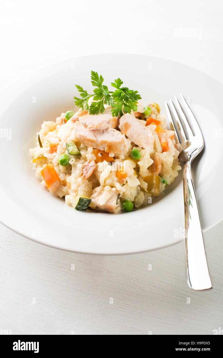 Risotto mit Gemüse und Hühnerfleisch serviert auf weißen Teller Stockfoto