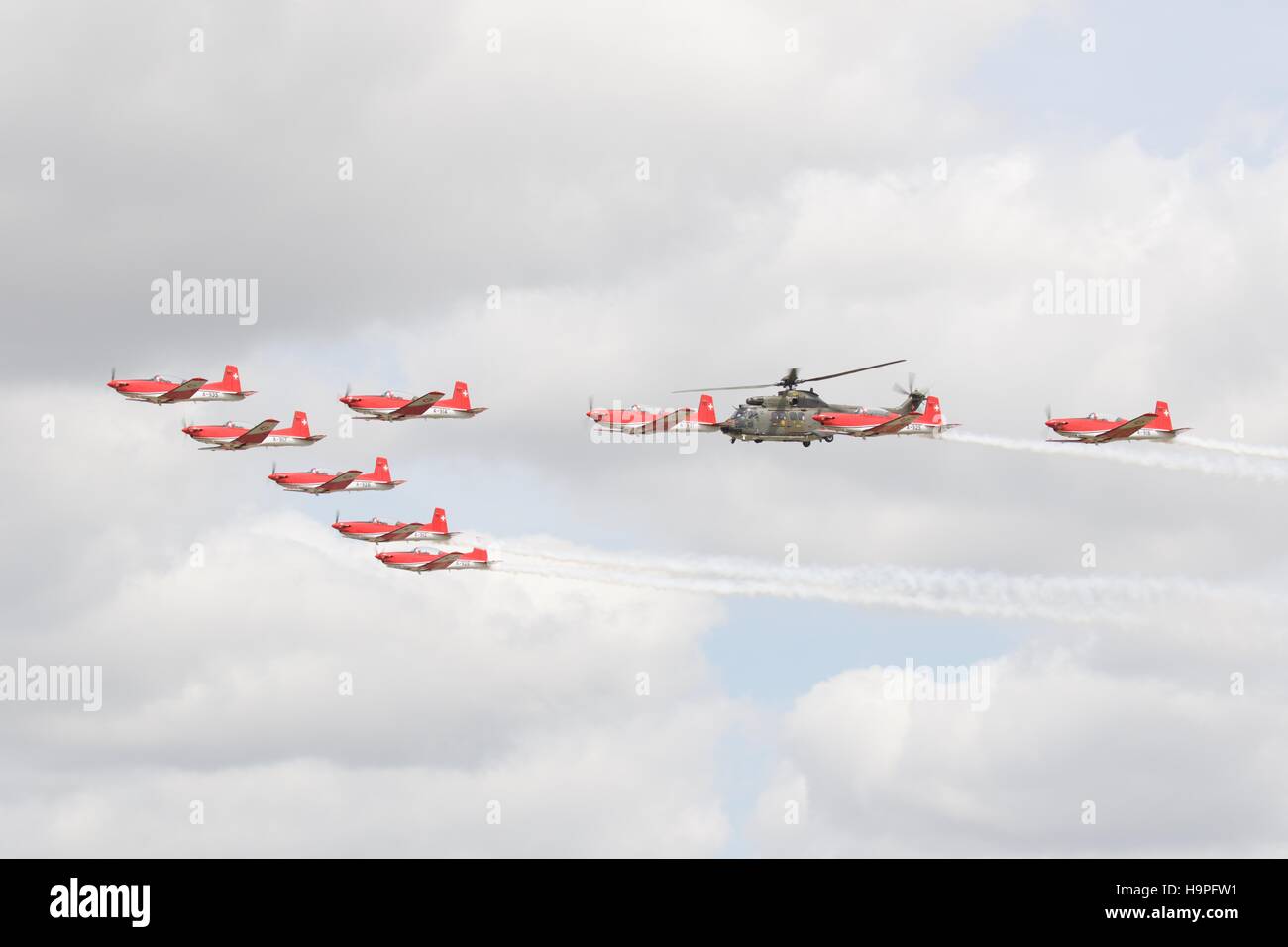 Schweizer Luftwaffe PC-7 Team im Formationsflug mit einem Super-Puma Stockfoto