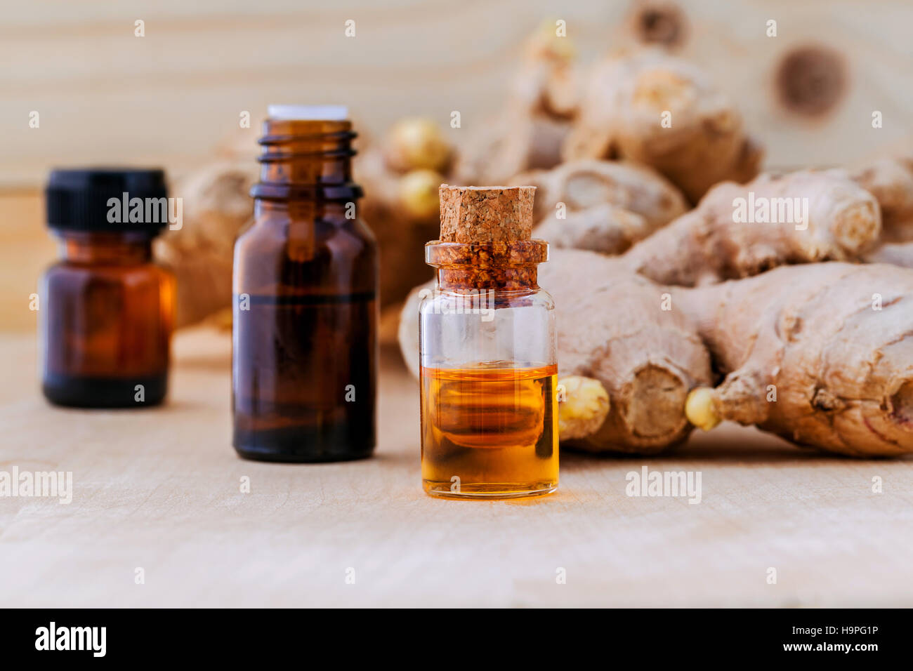 Flaschen von Ingwer Öl und Ingwer auf hölzernen Hintergrund mit selec Stockfoto