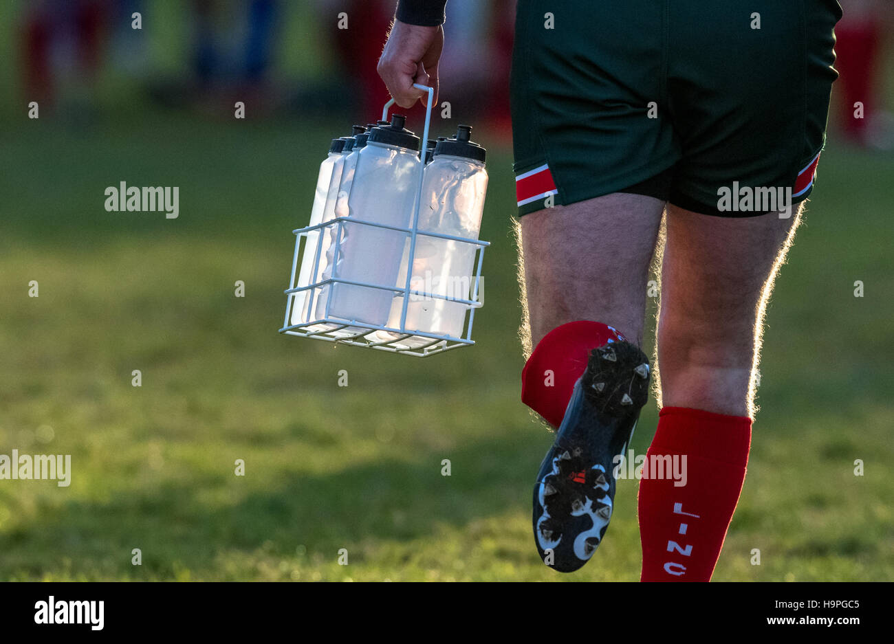 Rugby-Spieler tragen Wasser in Flaschen in einem Metallkäfig für die Teamplayer. Stockfoto