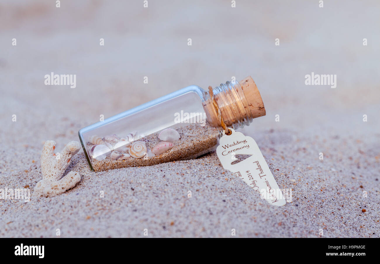 Nahaufnahme der Flasche Hochzeitseinladung mit Muschel und Papier Tag Veranstaltungsort am tropischen Strand. Stockfoto