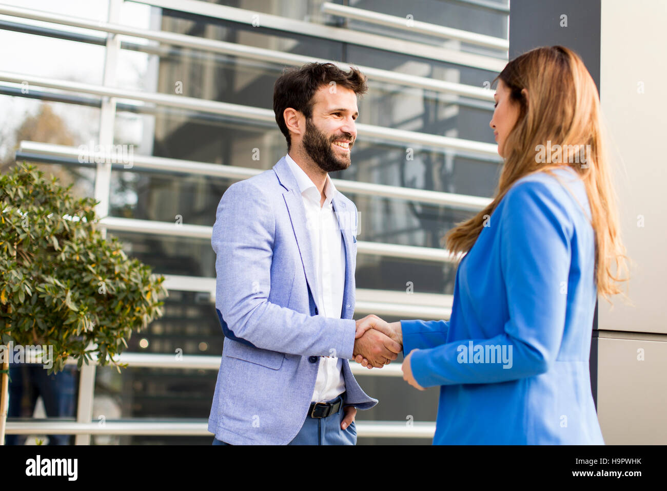 Junge Geschäftsleute schütteln sich die Hände vor dem Bürogebäude Stockfoto