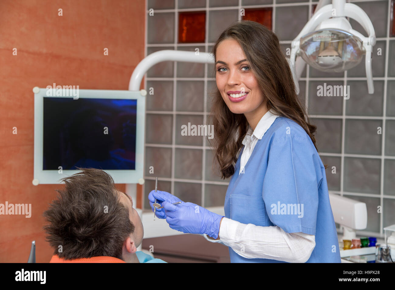 Junger Mann mit medizinischer Checkup in der Zahnarztpraxis durch die junge Ärztin Stockfoto