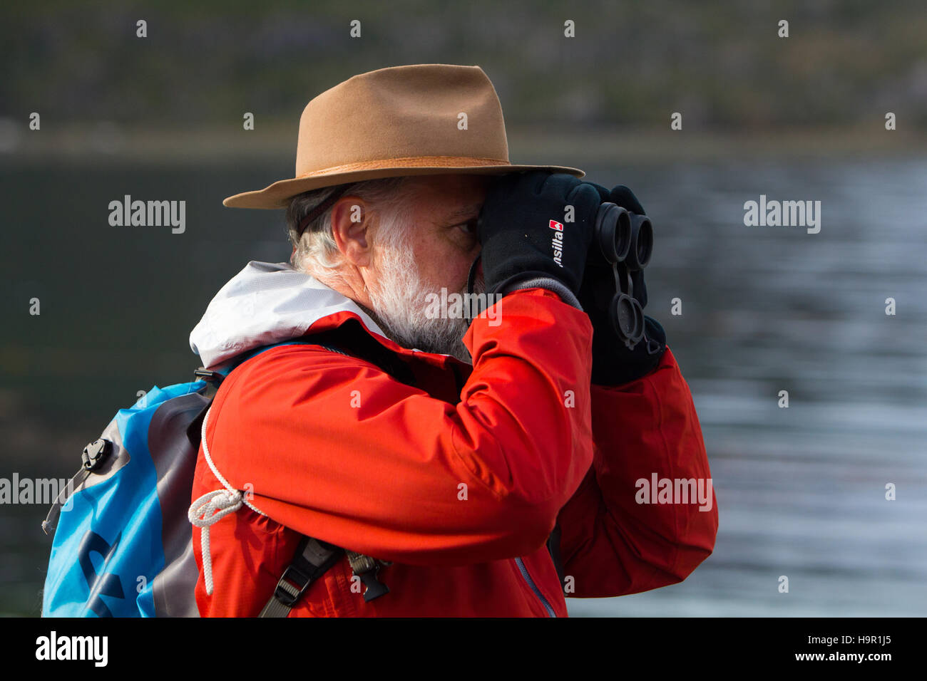 Ein Natur-Touristen auf der Suche durch sein Fernglas Vögel tragen einen hellen roten Mantel Stockfoto