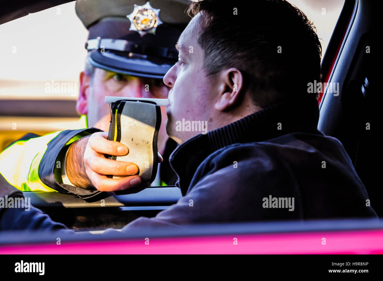 Belfast, Nordirland. 24. November 2016 - bläst ein Treiber in ein am Straßenrand handheld Alkohol Atem Tester Alkoholtester, während er von einem Polizisten Verkehr stattfindet. Bildnachweis: Stephen Barnes/Alamy Live-Nachrichten Stockfoto
