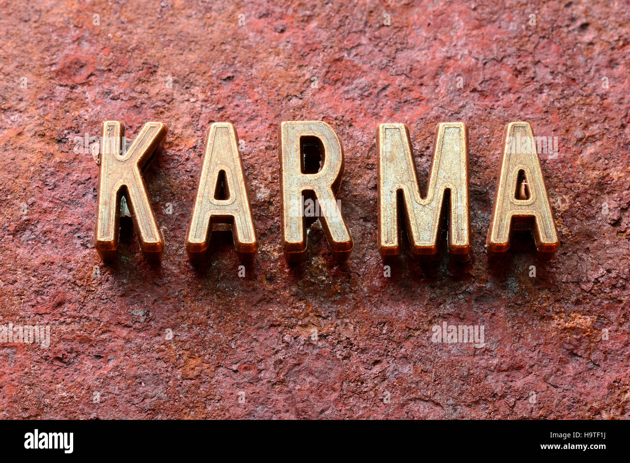 Karma-Wort, das aus metallischen Lettern auf rotem rostige Oberfläche Stockfoto