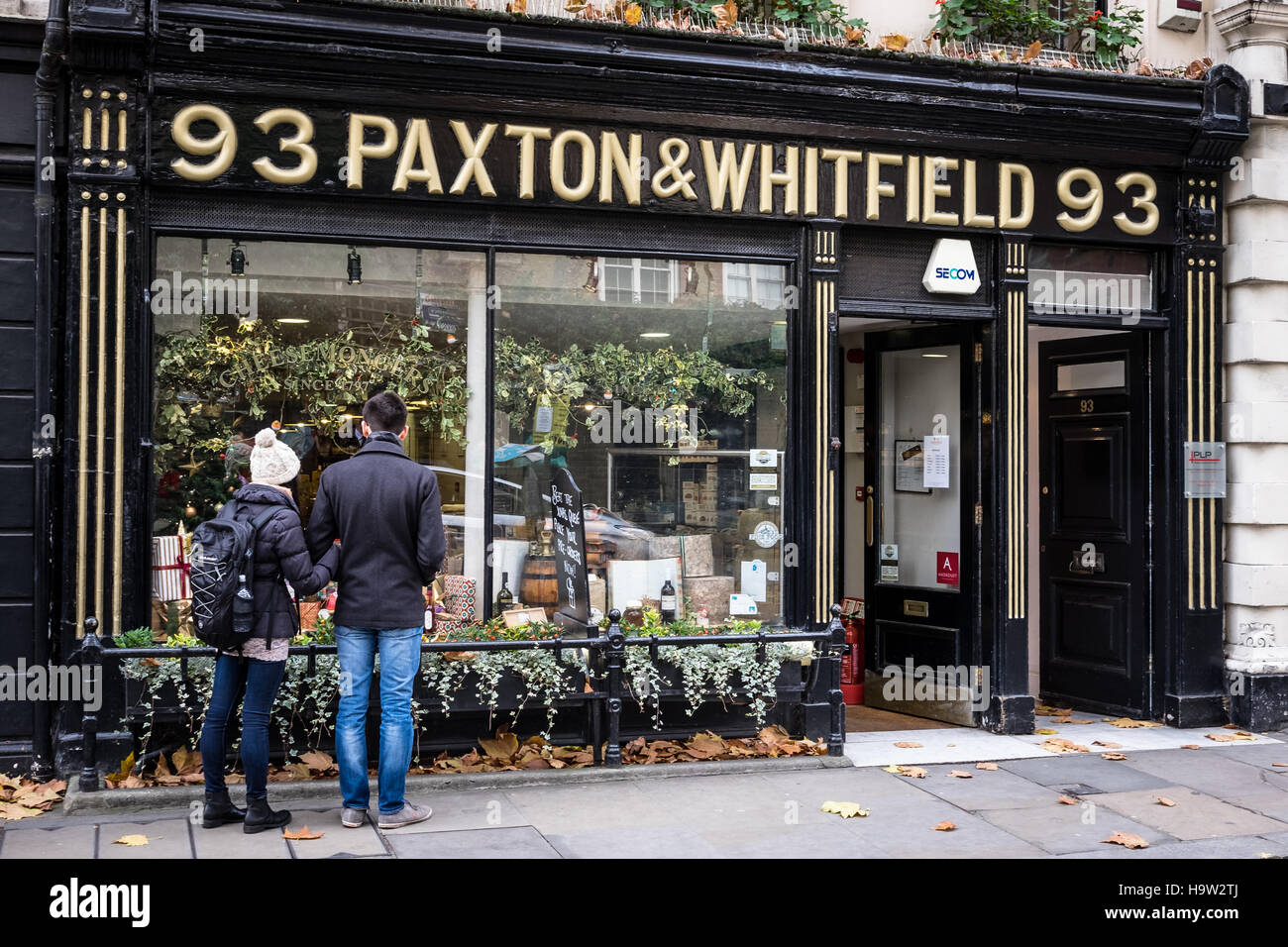 Ein junges Paar, Blick auf die Schaufenster von Paxton und Whitfield Cheesemongers in der Jermyn Street, London. Stockfoto